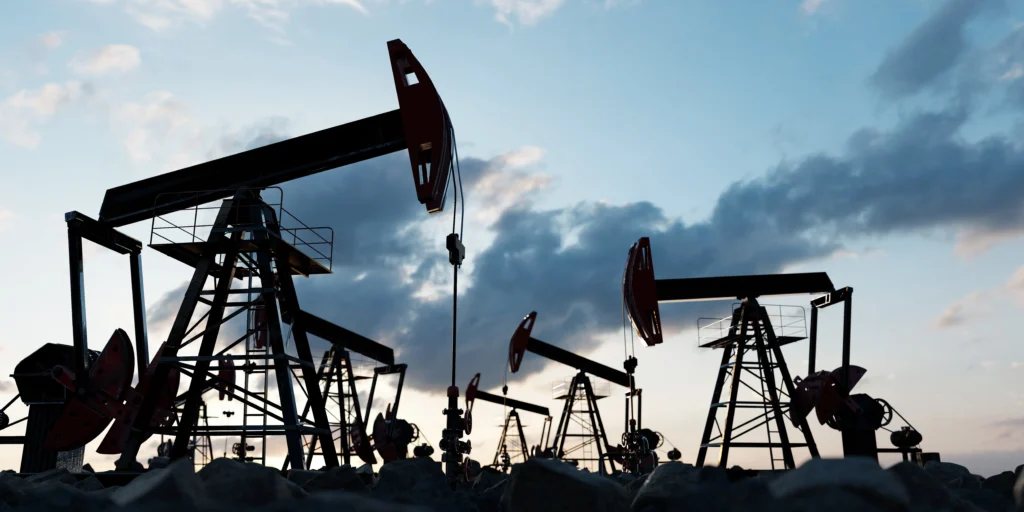 Oil pumpjacks operating at sunset in a large crude oil field